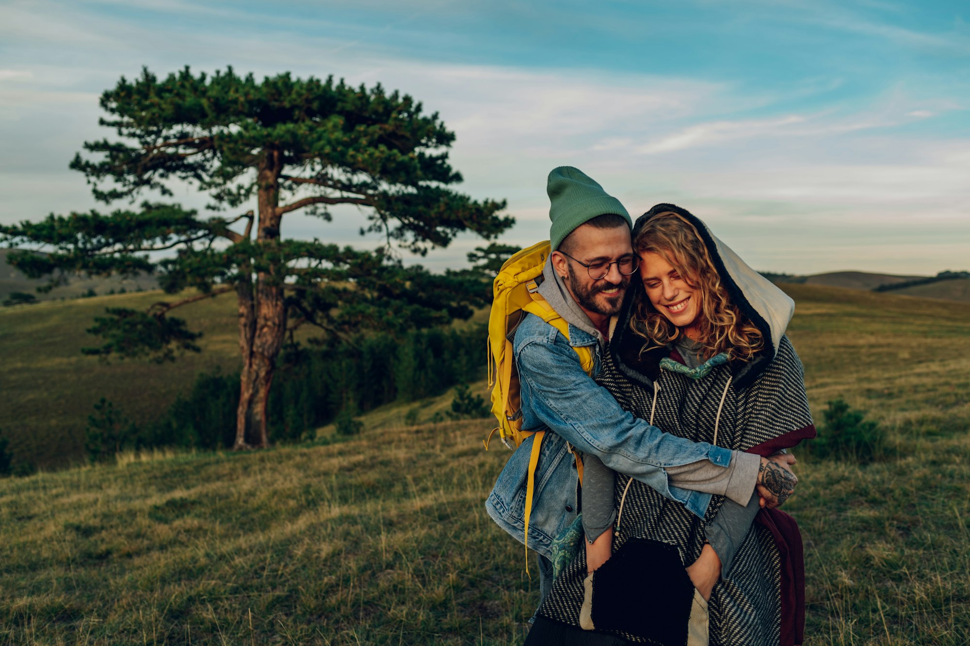 Couple of hikers embracing while walking on a mountain trail during a vacation
