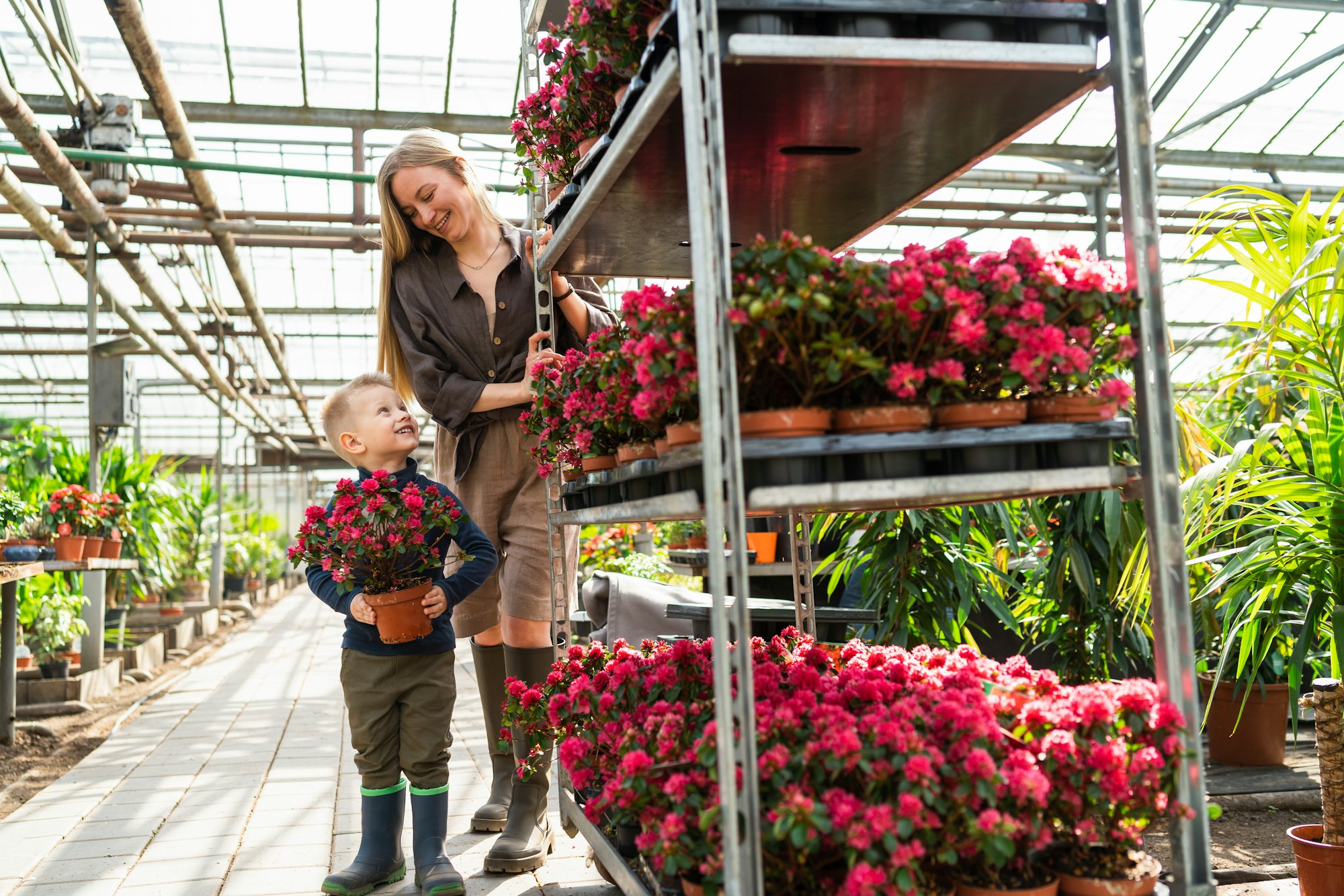 Little boy with a flower in a pot and his mom, a florist who pulls a cart with flowers