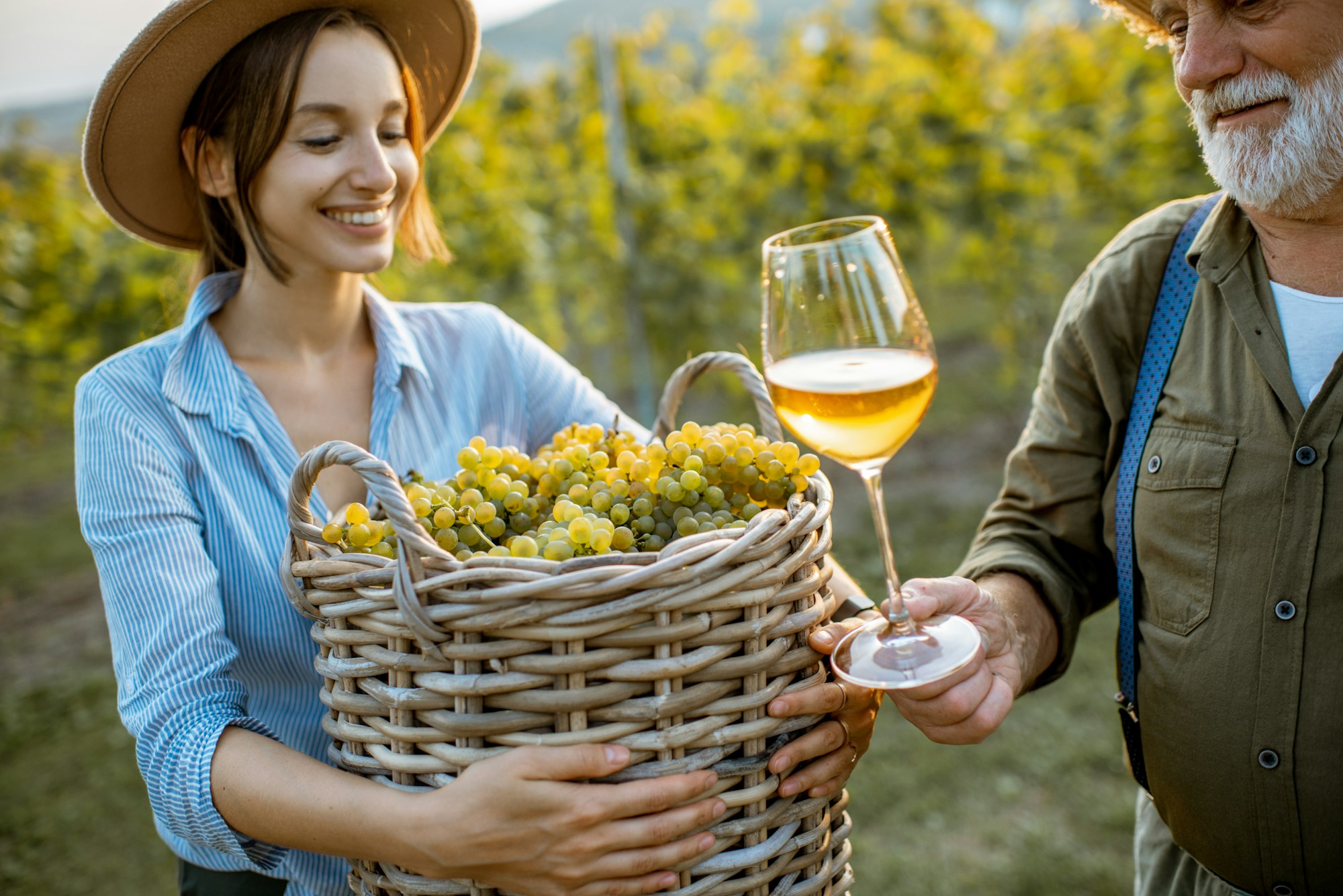 Senior man with young woman tasting wine on the vineyard